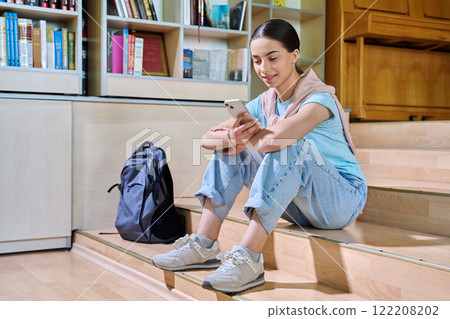 Teenage female student using smartphone, inside high school library 122208202
