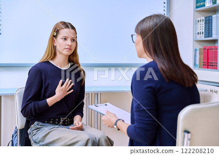 Sad serious teenage student girl talking with female school counselor, teacher Sad serious teenage student girl talking with female school counselor, teacher 122208210