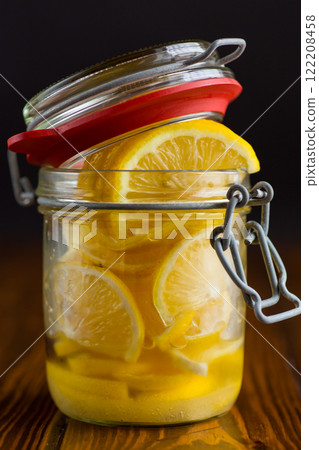 sliced lemons in sugar syrup in a glass jar, canned 122208458