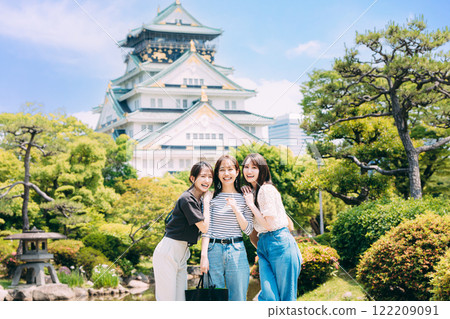 Women strolling through a garden with a view of Osaka Castle's castle tower 122209091