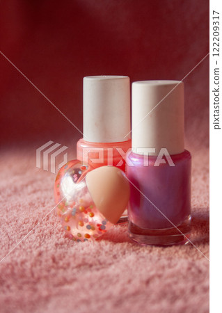 Close-up picture of cosmetic set in heart shape and nail polishes on pink background. Close-up picture of cosmetic set in heart shape and nail polishes on pink background. 122209317