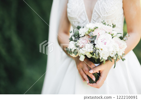 Bride holding big and beautiful wedding bouquet with flowers 122210091