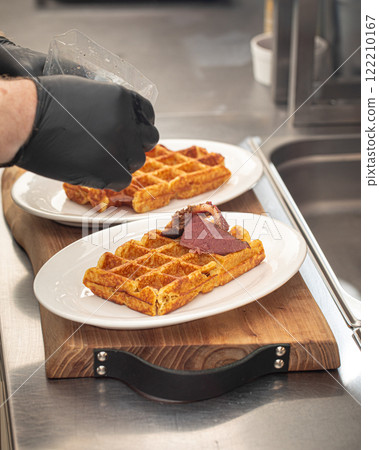 Chef putting pieces of beef brisket on waffles Chef putting pieces of beef brisket on waffles 122210167