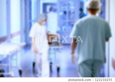 A blurred hospital corridor with patients and doctors in blue tinting. A blurred hospital corridor with patients and doctors in blue tinting. 122210255