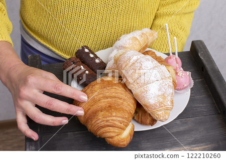 Hands hold a tray with sweets and pastries. 122210260
