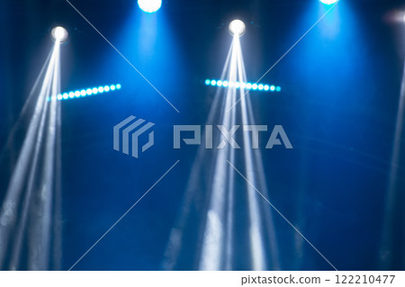 Blurred rays of light from stage spotlights on a blue stage background. 122210477
