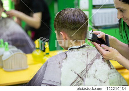 The boy gets a haircut at the barbershop. They do a short hairstyle. The boy gets a haircut at the barbershop. They do a short hairstyle. 122210484