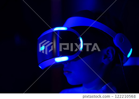 A person wearing a blue virtual reality headset. The person is looking at the camera. Concept of excitement and anticipation as the person prepares to enter the virtual world A person wearing a blue virtual reality headset. The person is looking at the camera. Concept of excitement and anticipation as the person prepares to enter the virtual world 122210568