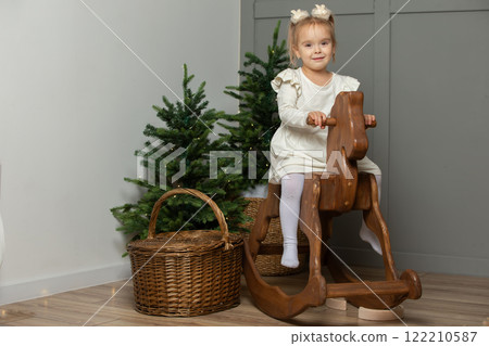 A girl on a horse gurney in a Christmas room. A girl on a horse gurney in a Christmas room. 122210587