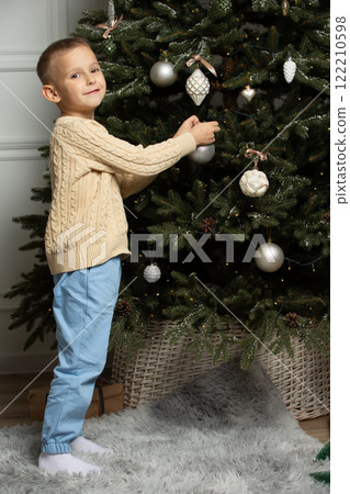 A little boy decorates a Christmas tree. A little boy decorates a Christmas tree. 122210598
