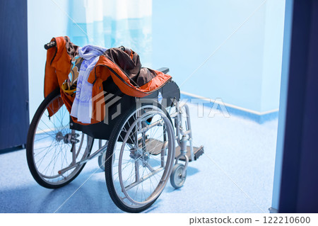 Wheelchair with things in the hospital corridor. The seriously ill patient was taken to the hospital. Wheelchair with things in the hospital corridor. The seriously ill patient was taken to the hospital. 122210600