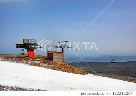 Cable car station overlooks stunning snow-covered landscape under clear blue skies. Copy space. 122211204