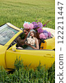 A young girl is sitting in a yellow convertible surrounded by bright flowers 122211447