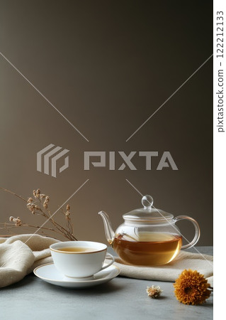 Warm tea set with a glass teapot and a white cup on a textured surface during a calm afternoon 122212133