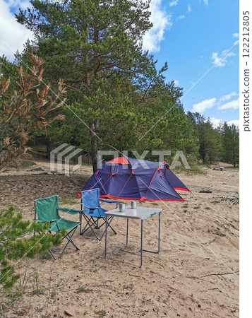 Camping with a tent, table and chairs on the sandy beach. Relaxation in nature 122212805