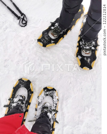 Two pairs of legs in snowshoes on winter landscape ready for an outdoor trek in a snowy environment 122212814