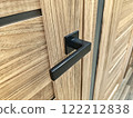 Modern black door handle on a wooden cabinet showcasing sleek design in a contemporary interior setting 122212838