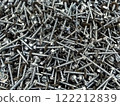 Close-up view of assorted metal screws and bolts scattered on a workbench in a workshop environment 122212839