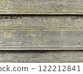 Weathered wooden wall with peeling paint and moss growth in a rural setting. Natural background 122212841