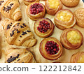 Freshly baked pastries with fruit fillings and chocolate croissants displayed on a wooden board in a bakery 122212842