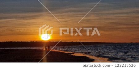 Sunset on the beach of the Gulf of the Baltic Sea. Human silhouettes on the beach. Sunset on the beach of the Gulf of the Baltic Sea. Human silhouettes on the beach. 122213526