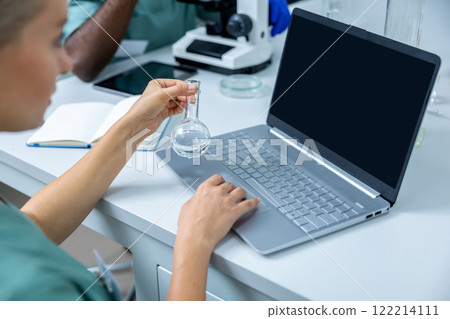 Medical woman wearing coat working as scientist in office using laptop for online research 122214111