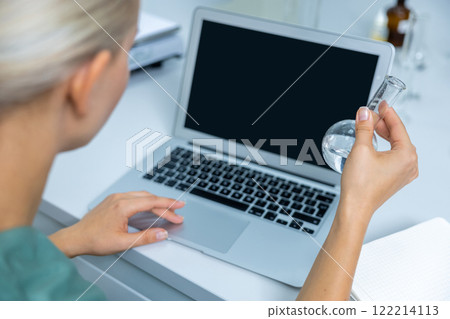Female scientist with blonde hair in lab analyzing test results on computer for biotechnology 122214113