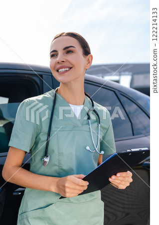 Female doctor standing near the car with a prescription list in hands Female doctor standing near the car with a prescription list in hands 122214133