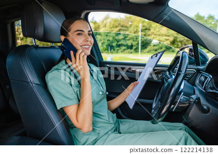 Female doctor sitting in the car and talking to the patient on the phone Female doctor sitting in the car and talking to the patient on the phone 122214138