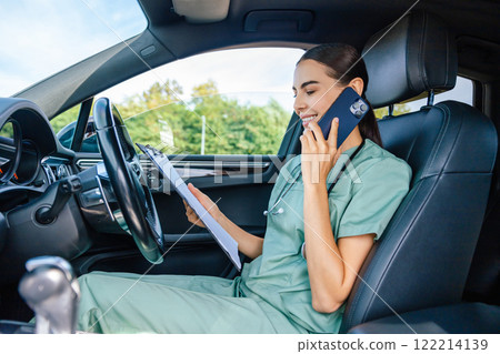 Female doctor sitting in the car and talking to the patient on the phone 122214139