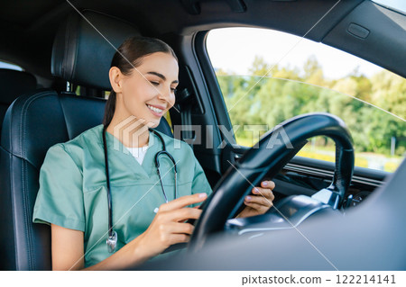 Smiling positive young woman in lab suit driving a car 122214141