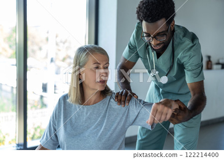 Doctor or physiotherapist g treating injured arm of senior female patient stretching and exercise Doctor or physiotherapist g treating injured arm of senior female patient stretching and exercise 122214400