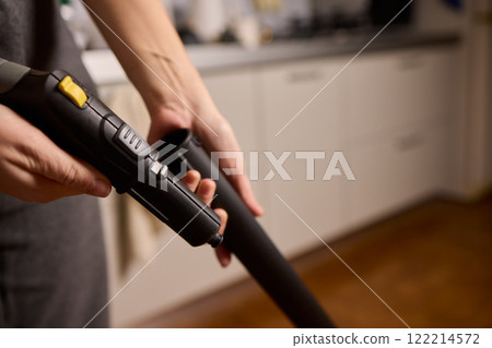 Hands actively using a vacuum cleaner in a clean and modern kitchen environment Hands actively using a vacuum cleaner in a clean and modern kitchen environment 122214572