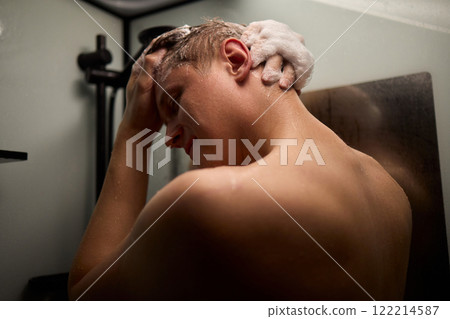A person is enjoying a refreshing shower while using shampoo in a modern bathroom setting A person is enjoying a refreshing shower while using shampoo in a modern bathroom setting 122214587