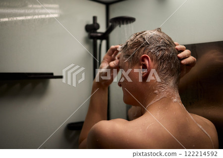 A person is enjoying a refreshing shower while using shampoo in a modern bathroom setting 122214592