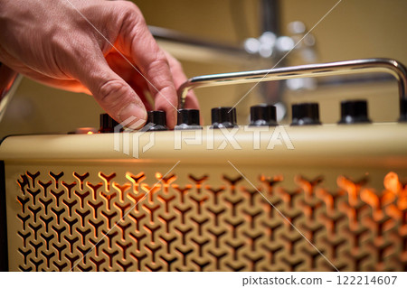 A musician is adjusting the amplifier settings for optimal sound quality during a performance 122214607