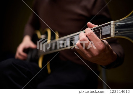 Close Up of Hands Playing a Guitar in a Warm and Cozy Setting Filled with Music and Art Close Up of Hands Playing a Guitar in a Warm and Cozy Setting Filled with Music and Art 122214613