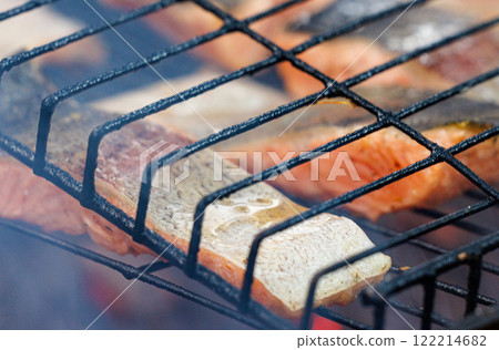 Grilled trout fish sizzling on a barbecue grill during a summer gathering by the lake Grilled trout fish sizzling on a barbecue grill during a summer gathering by the lake 122214682