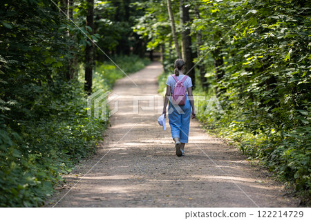 Walking along a peaceful forest path surrounded by lush greenery on a sunny day 122214729