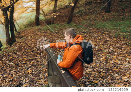 Blonde male with bottle of coffee pointing finger outdoors, he hiking on woodland, rear view. Active lifestyle concept. Trip, travel and people banner. High quality photo Blonde male with bottle of coffee pointing finger outdoors, he hiking on woodland, rear view. Active lifestyle concept. Trip, travel and people banner. High quality photo 122214969