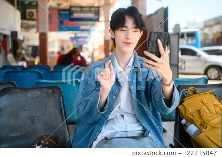 Cheerful young traveler making a video call at in a public transportation terminal Cheerful young traveler making a video call at in a public transportation terminal 122215047