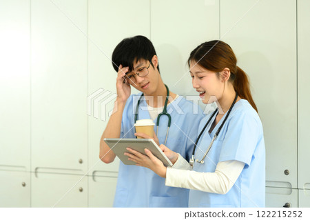 Young female medical student explaining details on digital tablet to her classmate Young female medical student explaining details on digital tablet to her classmate 122215252