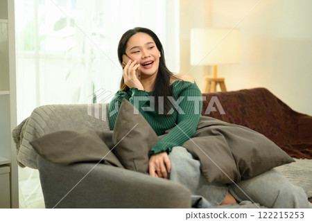 Attractive young woman in a green sweater enjoying a phone conversation at home Attractive young woman in a green sweater enjoying a phone conversation at home 122215253