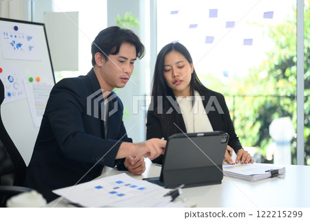 Two businesspeople analyzing data displayed on digital tablet at bright office Two businesspeople analyzing data displayed on digital tablet at bright office 122215299