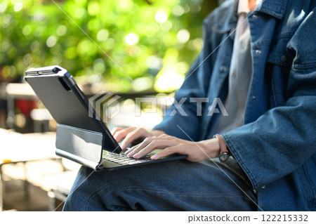 Cropped shot of young man using digital tablet in a serene outdoor cafe Cropped shot of young man using digital tablet in a serene outdoor cafe 122215332