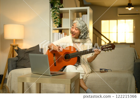 Happy senior woman enjoying a music lesson on her laptop at home 122215366