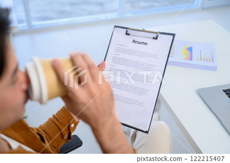Cropped shot of HR manager sipping coffee reviewing resume during remote online job interview Cropped shot of HR manager sipping coffee reviewing resume during remote online job interview 122215407