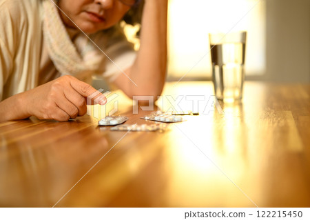 Cropped shot senior woman organizing or preparing to take her medication on a table. Cropped shot senior woman organizing or preparing to take her medication on a table. 122215450