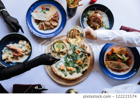 Elegant dinner celebration with gourmet dishes, pizza, and wine toasting at a festive table setting 122215574