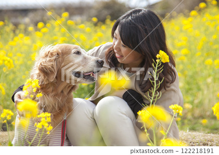 黃金獵犬和主人在油菜花田裡擁抱 122218191